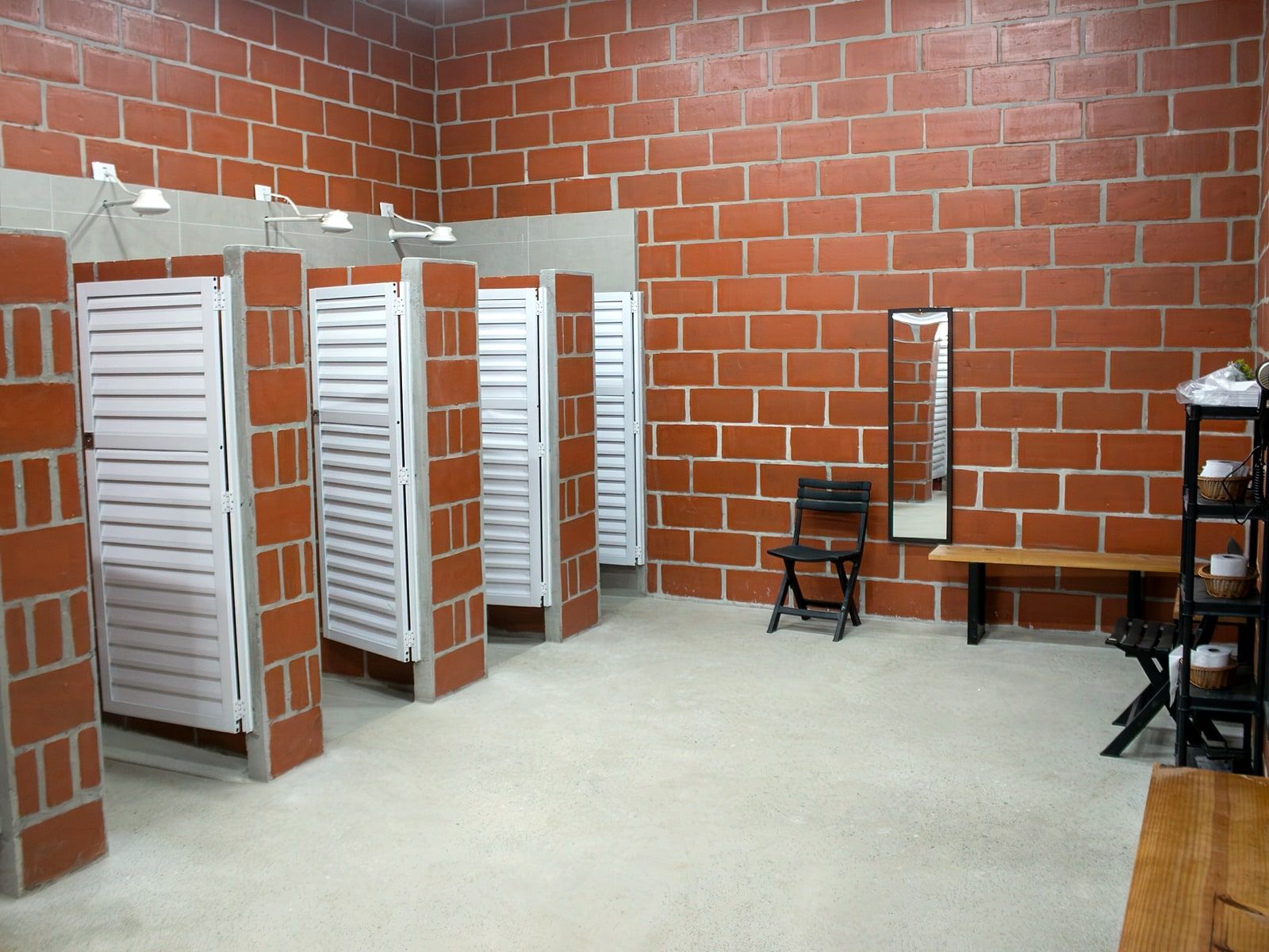 Vestiário por dentro: boxes de chuveiro, espelho e banco